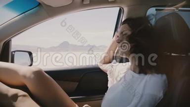 特写POV拍摄的快乐放松的女人，头发随风飘动在盐湖沙漠的汽车乘客座位上。